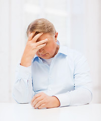 Image showing stressed old man holding head at home