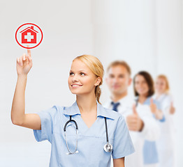 Image showing smiling doctor or nurse pointing to hospital icon