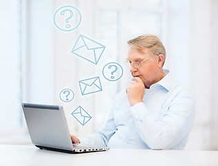 Image showing old man in eyeglasses working with laptop at home