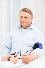 Image showing female doctor or nurse measuring blood pressure