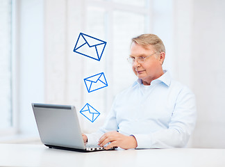 Image showing old man in eyeglasses working with laptop at home