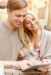 Image showing smiling couple with tablet pc computer in cafe