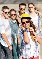 Image showing teenage girl with headphones and friends outside