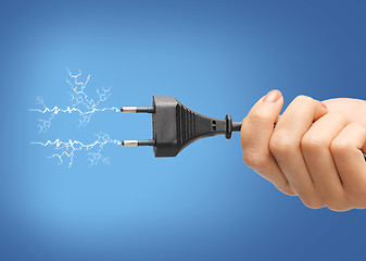 Image showing hand holding black electrical plug with wire