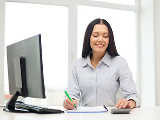 Image showing woman with computer, notebook and calculator