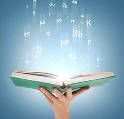 Image showing hand holding open book with magic lights