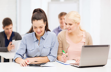 Image showing two smiling students with laptop and tablet pc