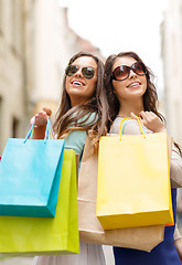 Image showing two girls in sunglasses with shopping bags in ctiy