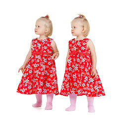 Image showing two identical twin girls in red dresses looking