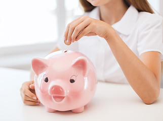 Image showing smiling child putting coin into big piggy bank