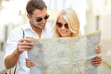 Image showing smiling couple in sunglasses with map in the city