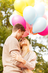 Image showing smiling couple with colorful balloons in park
