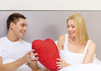 Image showing smiling couple in bed with red heart shape pillow