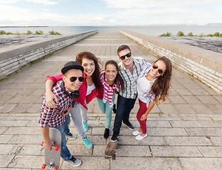 Image showing smiling teenagers with skates outside