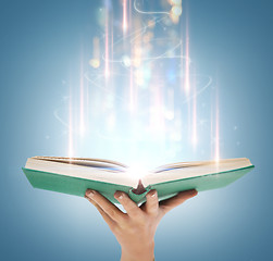 Image showing hand holding open book with magic lights