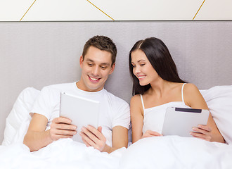 Image showing smiling couple in bed with tablet pc computers