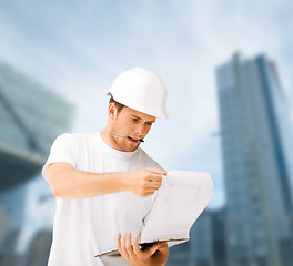 Image showing male architect in helmet looking at blueprint