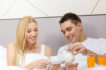 Image showing smiling couple having breakfast in bed in hotel