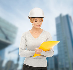 Image showing female contractor in helmet with blueprint