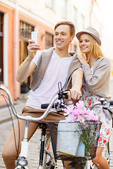 Image showing couple with bicycles and smartphone in the city