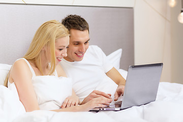 Image showing smiling couple in bed with laptop computer