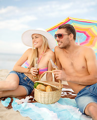 Image showing smiling couple having picnic on the beach