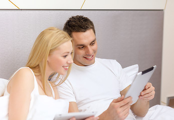 Image showing smiling couple in bed with tablet pc computers