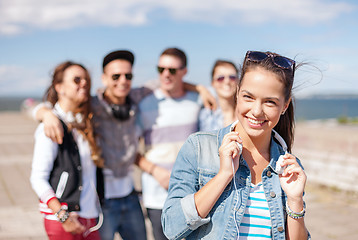 Image showing teenage girl with headphones and friends outside