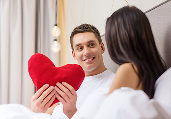 Image showing smiling couple in bed with red heart shape pillow