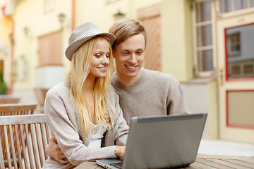 Image showing smiling couple with laptop computer in cafe