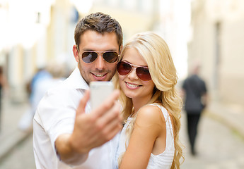 Image showing smiling couple with smartphone in the city
