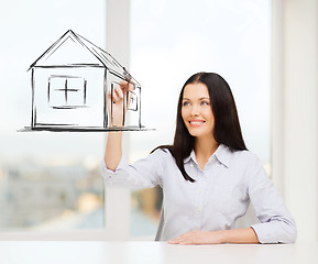 Image showing smiling woman drawing house on virtual screen