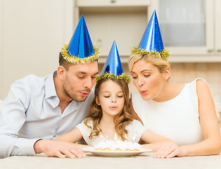 Image showing smiling family in blue hats with cake