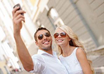 Image showing smiling couple with smartphone in the city