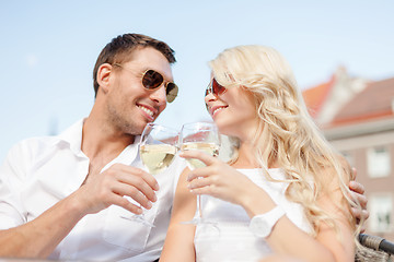 Image showing smiling couple in sunglasses drinking wine in cafe