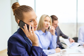 Image showing smiling business team with smartphones in office