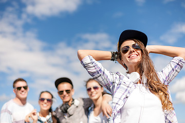 Image showing teenage girl with headphones and friends outside