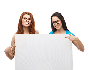 Image showing two smiling girls with eyeglasses and blank board