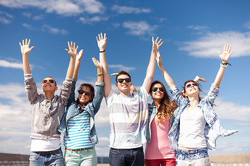 Image showing group of smiling teenagers holding hands up