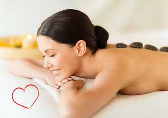 Image showing smiling woman in spa salon with hot stones