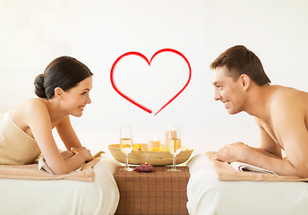 Image showing smiling couple with candles and drinks in spa