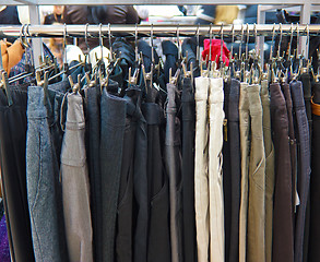 Image showing group different colored jeans hanging on a hanger in store