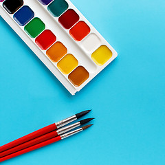 Image showing brushes watercolors paints for children on blue background