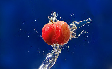Image showing Red Apple drops in the jet of water sprays on blue texture