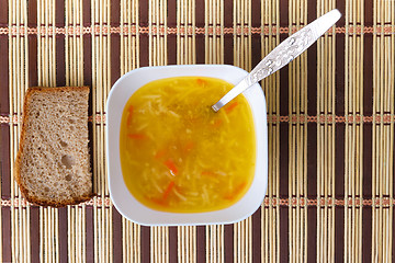 Image showing soup of bowl with a spoon and bread on the mat