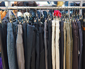 Image showing different group colored jeans hanging on a hanger in store shop