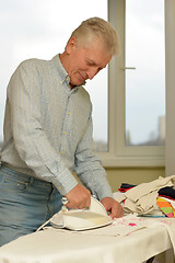 Image showing Senior man ironing
