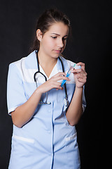 Image showing Young female doctor with stethoscope and syringe