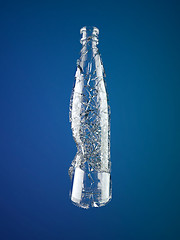 Image showing Broken empty glass bottle over blue