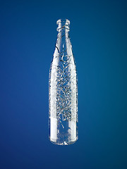 Image showing Shattered empty glass bottle over blue